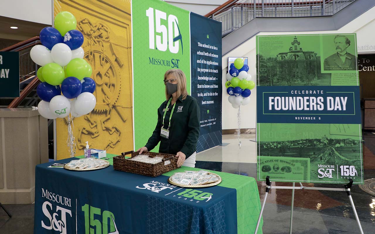 Woman stands behind a table offering cookies as a giveaway